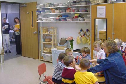 Participants watch a teacher work with a small group of children in the studio.